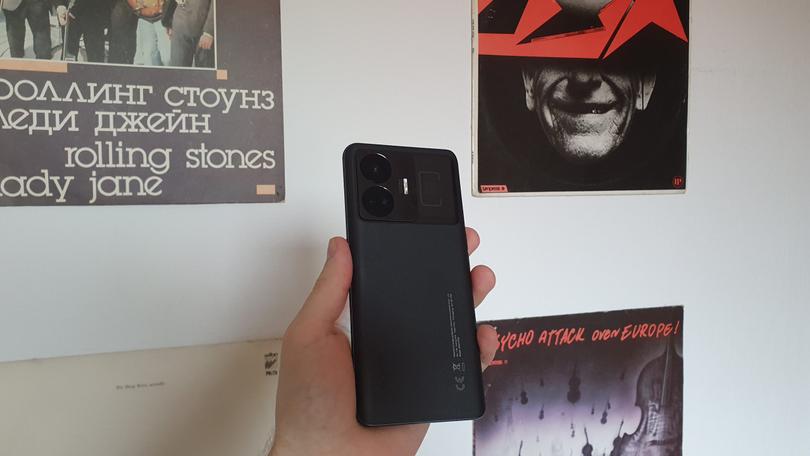 Smartfon realme GT3 w kolorze czarnym na tle białej ściany.